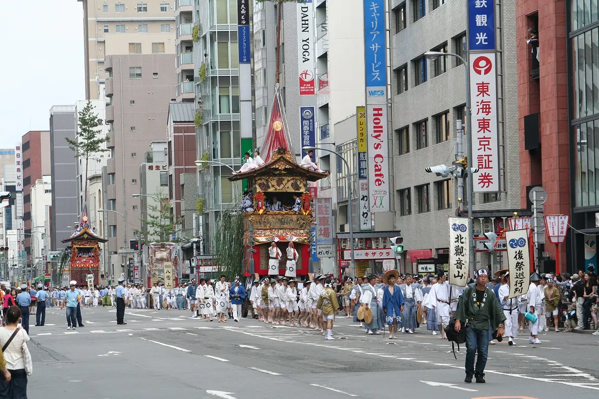 A tall wooden yamaboko float lit by lanterns on a closed Kyoto street at night