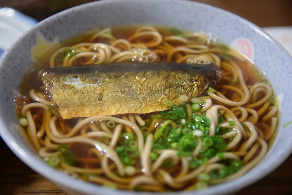 A bowl of soba in dashi topped with a whole simmered herring fillet
