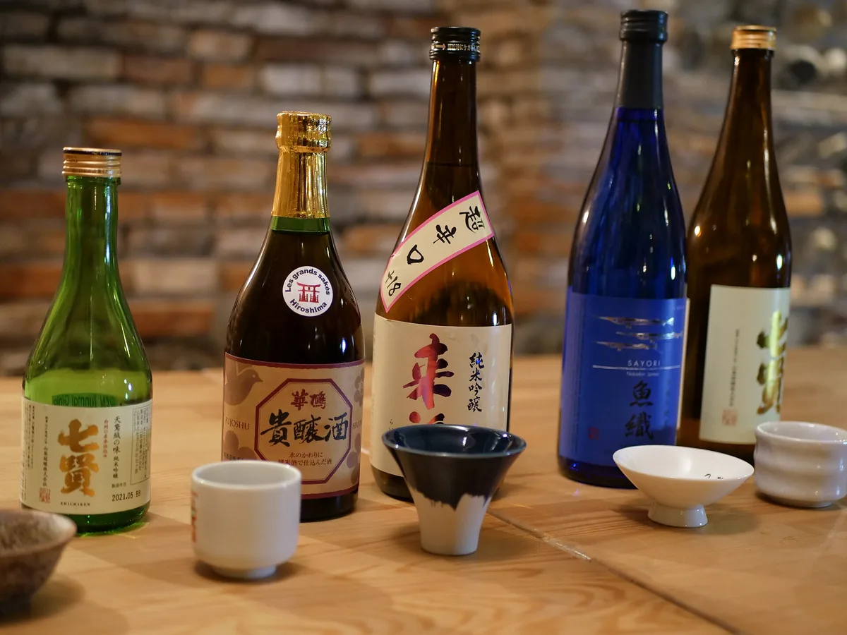 Small tasting glasses of sake lined up on a wooden counter