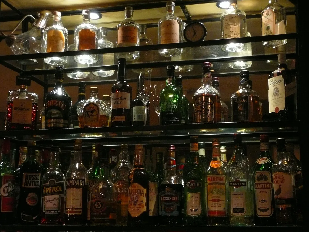 Rows of whisky bottles behind a wooden bar counter in Osaka