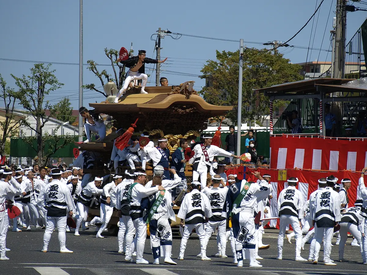 A wooden danjiri cart being hauled at speed around a corner in Kishiwada