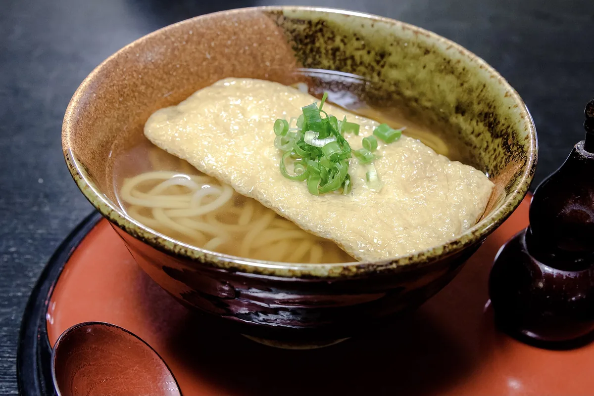 A bowl of kitsune udon with a sheet of sweet fried tofu on top