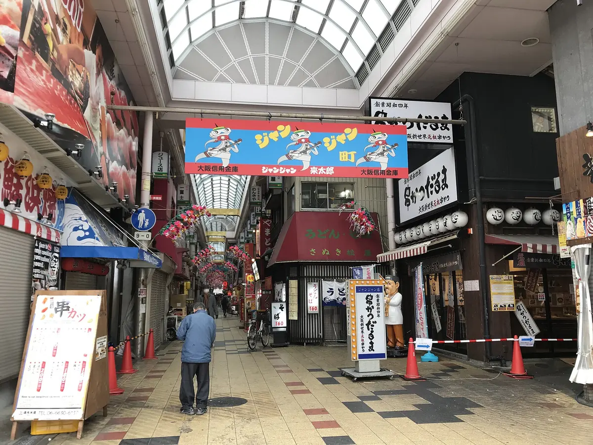 A street of illuminated kushikatsu signs leading toward Tsutenkaku tower