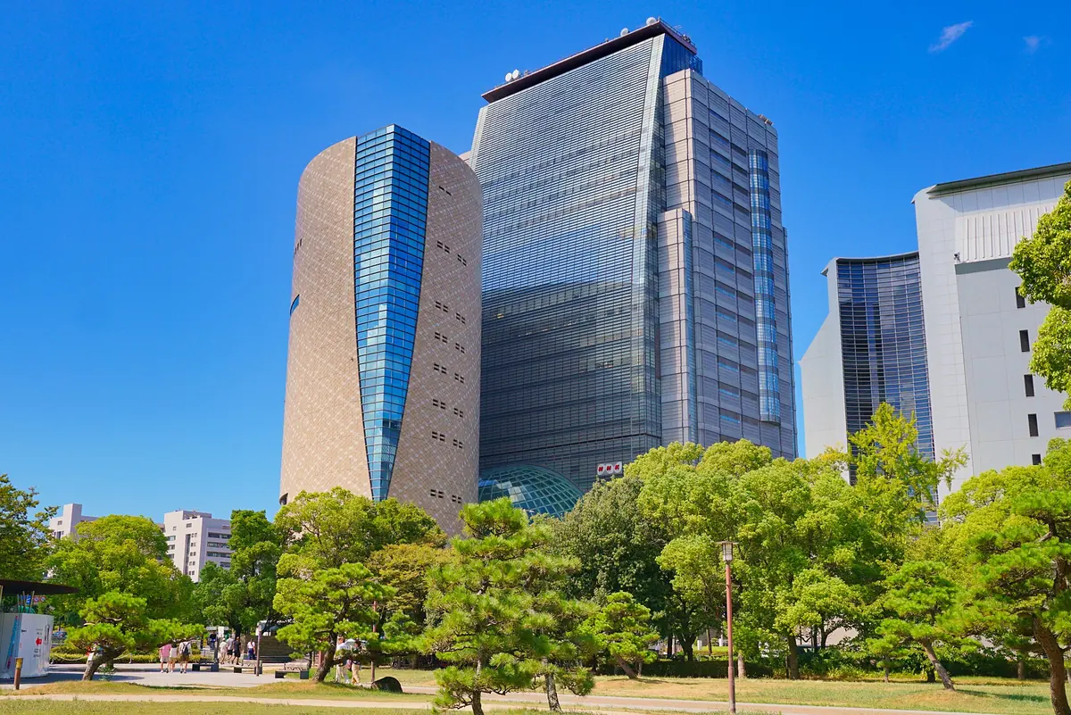 The curved glass tower of the Osaka Museum of History beside Osaka Castle