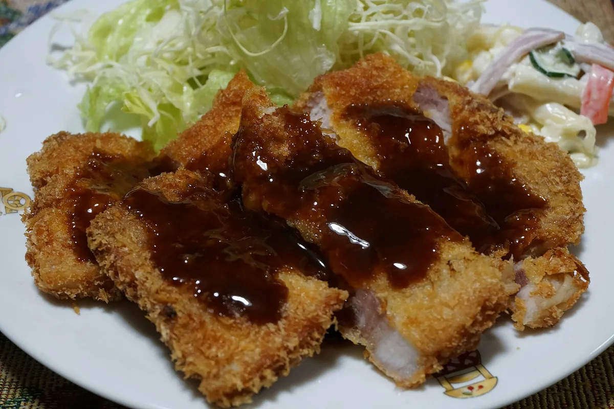 A sliced tonkatsu cutlet plated at a counter in Osaka