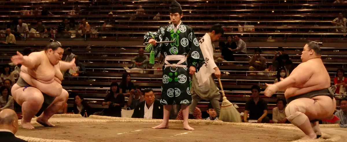 Two sumo wrestlers facing off on the clay ring at the Ryogoku Kokugikan