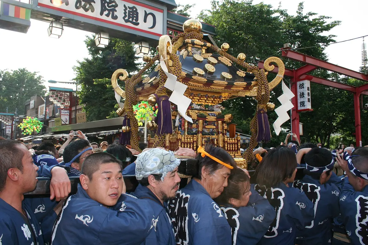 A gilded portable shrine carried on shoulders through a crowd in Asakusa