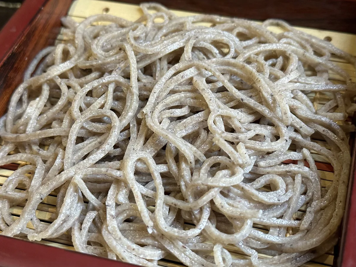 A bamboo tray of cold hand-cut soba noodles with dipping broth